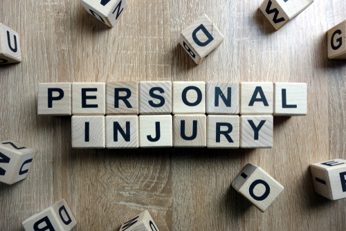 Wooden letter blocks spelling out ‘Personal Injury’ on a table, representing personal injury law and legal claims.