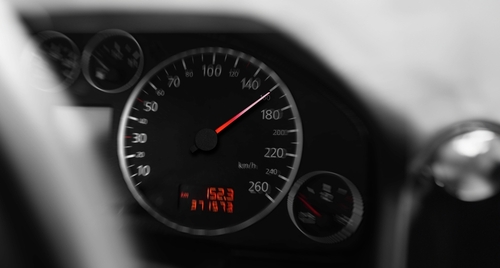 Close-up of a car speedometer showing high speed, with the needle pointing near 180 km/h, symbolizing reckless or high-speed driving.